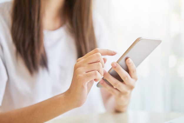 Donna che utilizza smartphone per l&#39;applicazione sul tavolo nella sala.