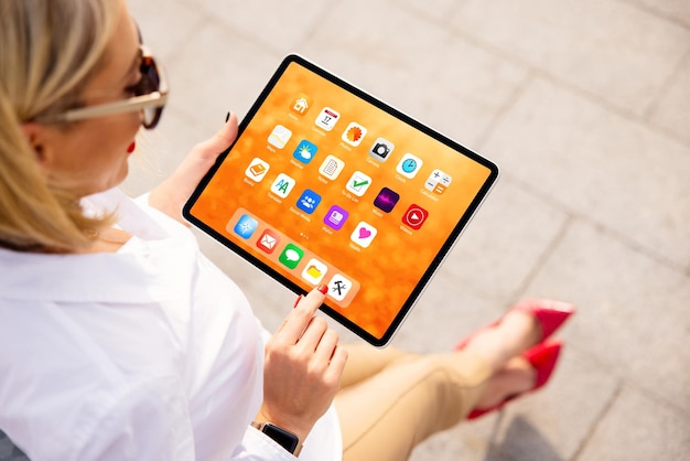 Donna che utilizza tablet con schermata iniziale colorata piena di icone di app di esempio