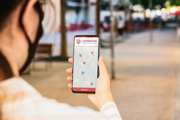 Donna che utilizza un'app di localizzazione del Coronavirus nel suo telefono mentre è in strada