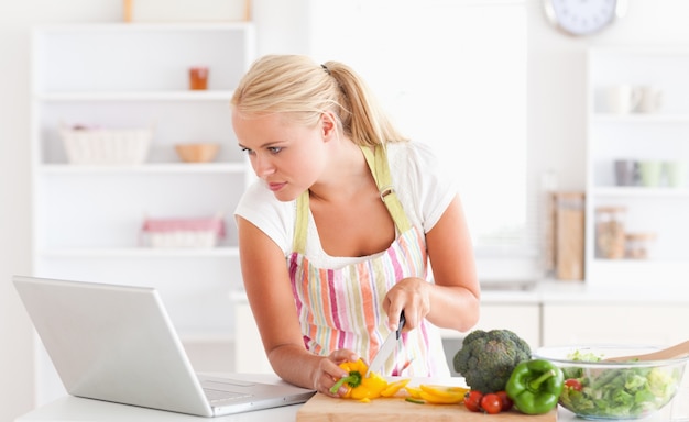 Donna che utilizza un computer portatile per cucinare