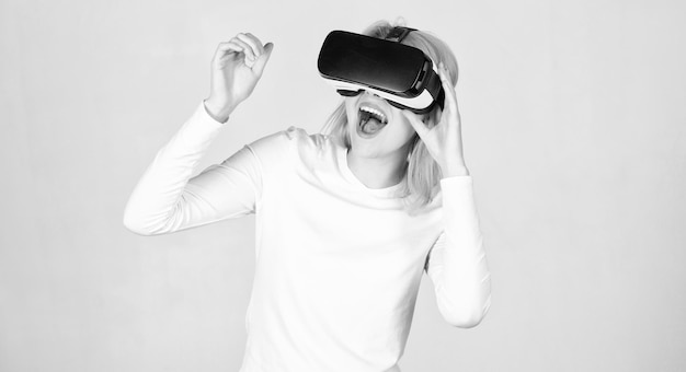 Donna che utilizza un dispositivo VR Donna che indossa occhiali per realtà virtuale su sfondo grigio La donna con