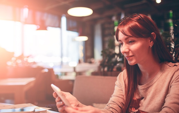 Donna che utilizza un telefono cellulare in ristorante, caffetteria, bar