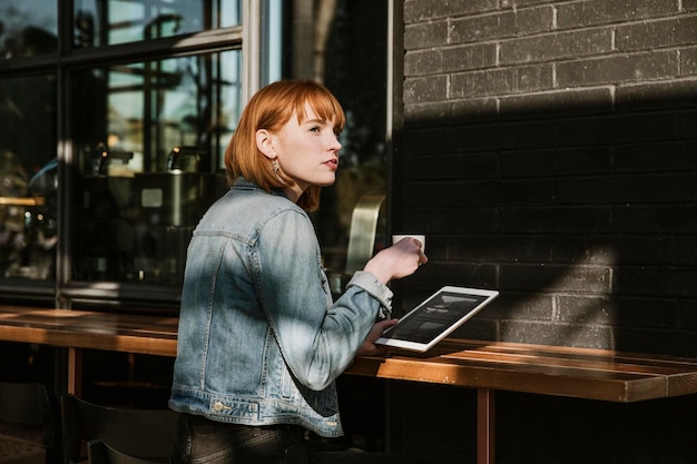 Donna che utilizza una tavoletta digitale in un bar