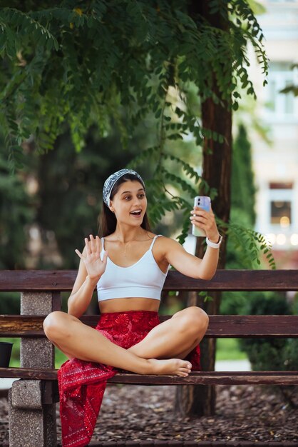 Donna che utilizza uno smartphone nel parco seduto su una panchina