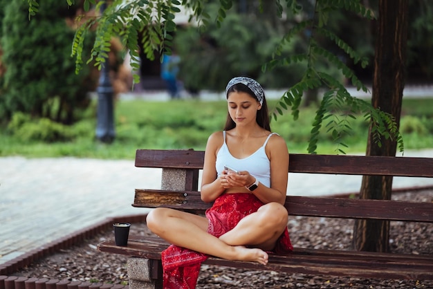 Donna che utilizza uno smartphone nel parco seduto su una panchina