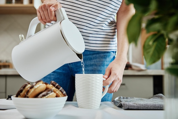 Donna che versa acqua dal bollitore per preparare il tè