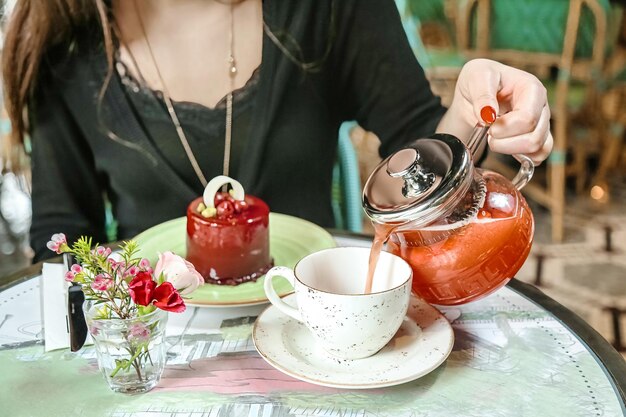 Donna che versa il tè dalla teiera nella tazza