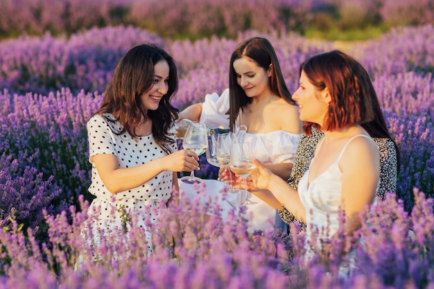 Donna che versa un vino in bicchieri a una festa di picnic per le sue amiche