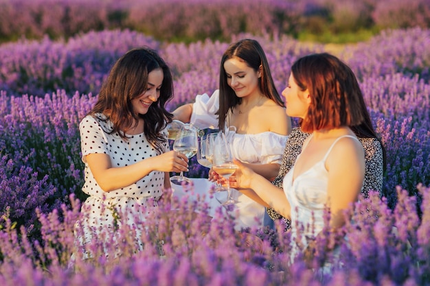 donna che versa vino bianco in bicchieri per le sue amiche