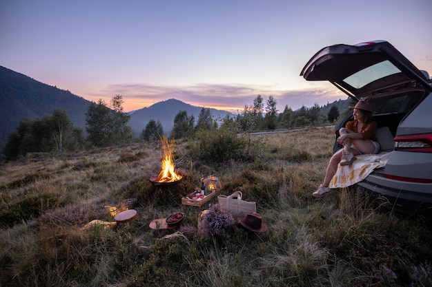 Donna che viaggia in macchina e fa un picnic in montagna