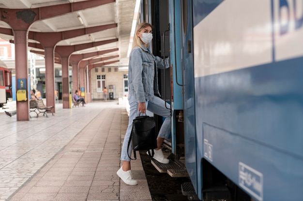 Donna che viaggia in treno indossando una maschera medica per protezione