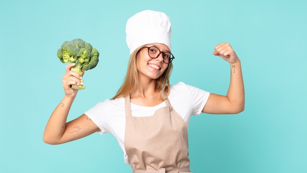 Donna chef bionda abbastanza giovane che tiene un broccolo