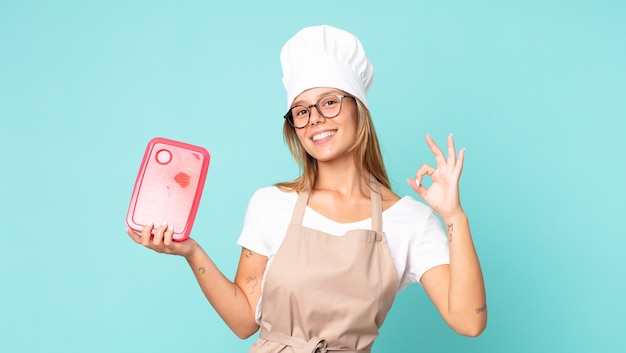 Donna chef bionda abbastanza giovane e con in mano un tupperware