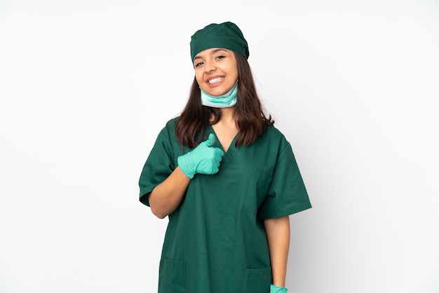Donna chirurgo in uniforme verde sul muro bianco dando un pollice in alto gesto