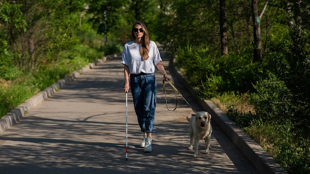 Donna cieca che cammina con il cane guida nel parco