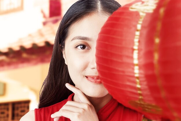 Donna cinese asiatica in un vestito cheongsam che tiene lanterna cinese. Buon Capodanno cinese