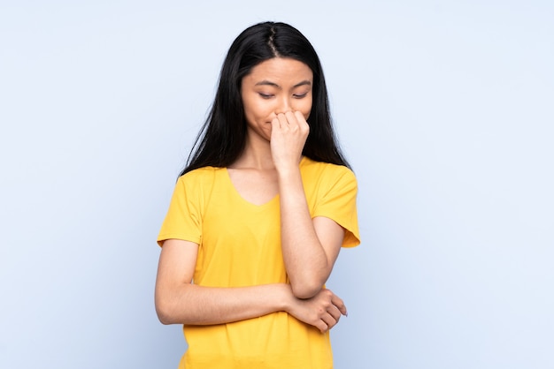 Donna cinese dell'adolescente isolata sulla parete blu che ha dubbi