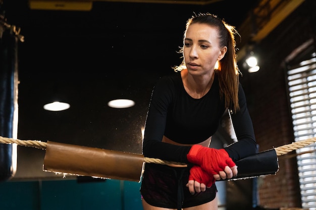 Donna combattente ragazza potere donna combattente con pugilato rosso avvolge bende protettive in piedi sulla boxe