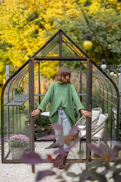 Donna come giardiniere vicino alla serra nel cortile