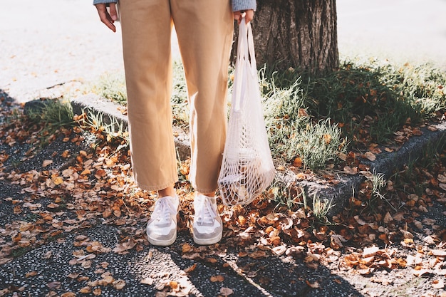 donna con acquisto in sacchetto di rete riutilizzabile in cotone sullo sfondo del negozio di rifiuti zero shop