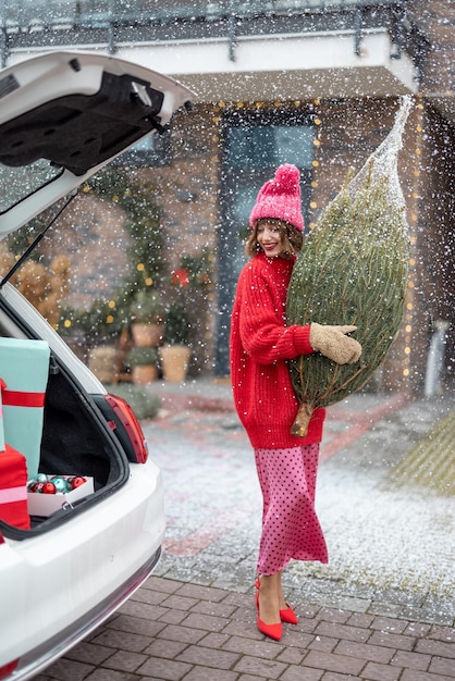 Donna con albero di Natale avvolto sul portico della sua casa