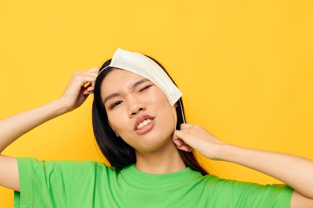 Donna con aspetto asiatico che posa indossando una maschera medica divertimento di sicurezza isolato sfondo inalterato
