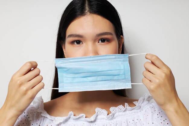 Donna con aspetto asiatico modello di studio di protezione con maschera medica inalterato