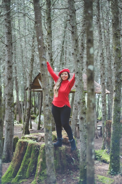 Donna con atteggiamento positivo su un ceppo di albero coperto di muschio nel mezzo della foresta