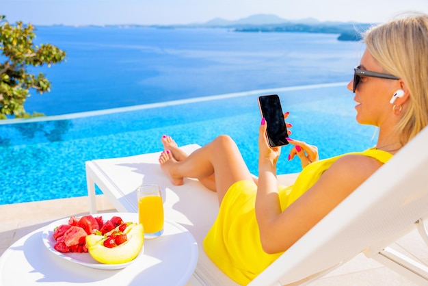 Donna con auricolari tramite cellulare in piscina