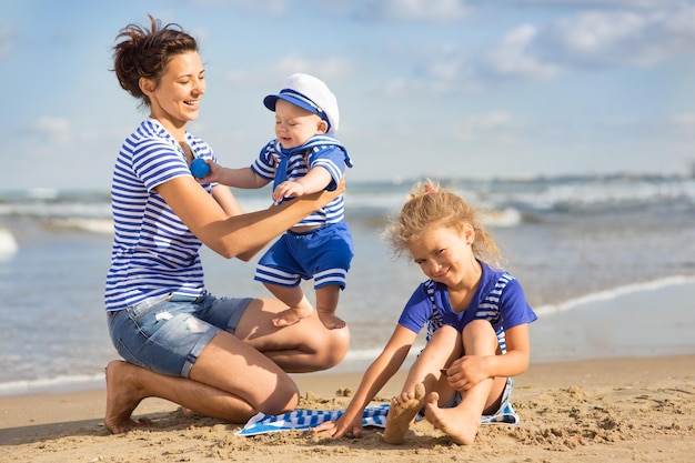 Donna con bambini che giocano sulla spiaggia, mamma con un bambino piccolo e bambino nella natura