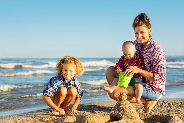 Donna con bambini che giocano sulla spiaggia, mamma con un bambino piccolo e bambino nella natura