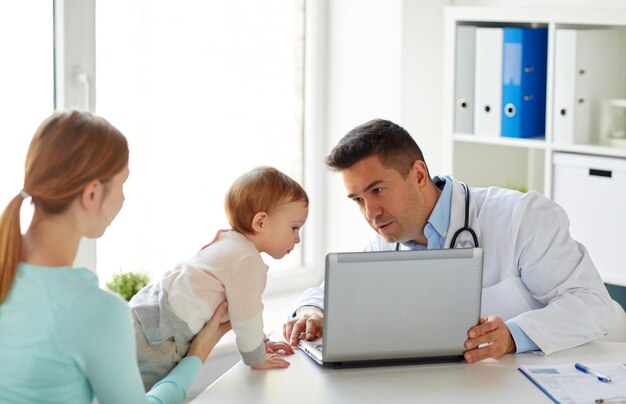 donna con bambino e dottore con laptop in clinica