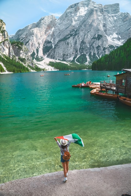 Donna con bandiera italiana sulla spiaggia del lago di Braies nelle montagne delle Dolomiti copia spazio vacanze estive