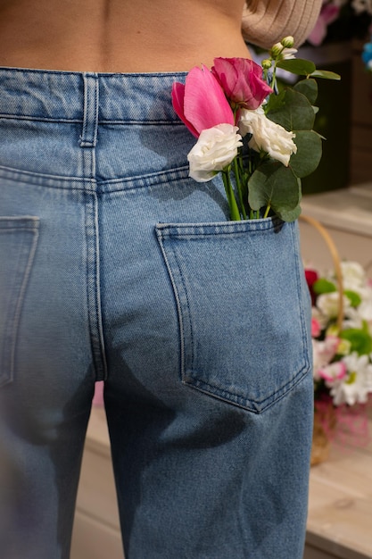 Donna con bellissimi fiori teneri nella tasca posteriore dei jeans Donna accoltella alla telecamera Un piccolo bouquet di fiori di campo in una tasca posteriore