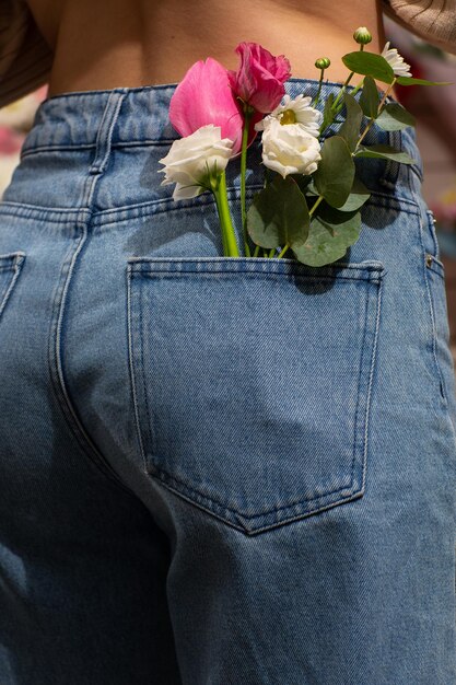 Donna con bellissimi fiori teneri nella tasca posteriore dei jeans Donna accoltella alla telecamera Un piccolo bouquet di fiori di campo in una tasca posteriore