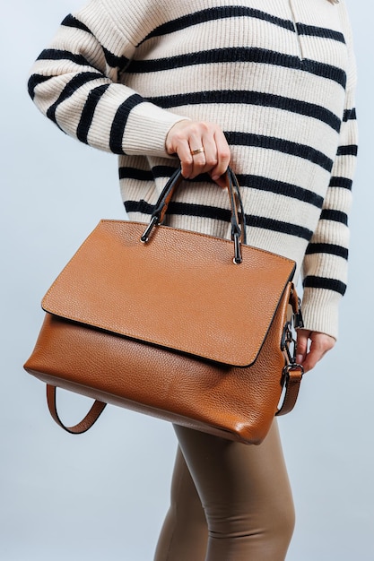 Donna con borsa in pelle marrone isolata su sfondo bianco Elegante pochette Foto verticale del primo piano