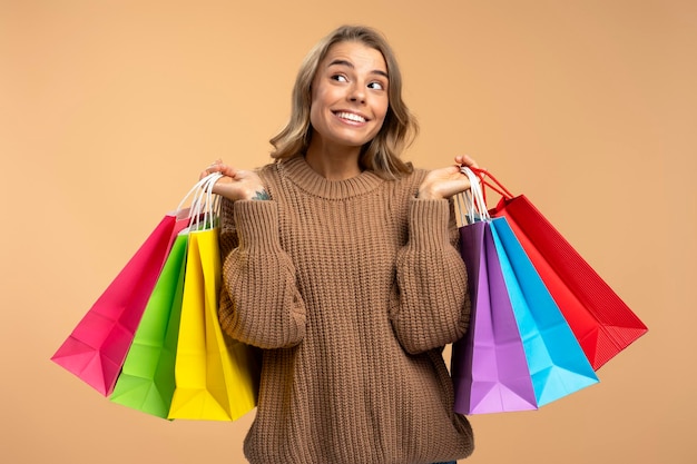 donna con borse della spesa colorate che guarda lontano scegliendo qualcosa di isolato