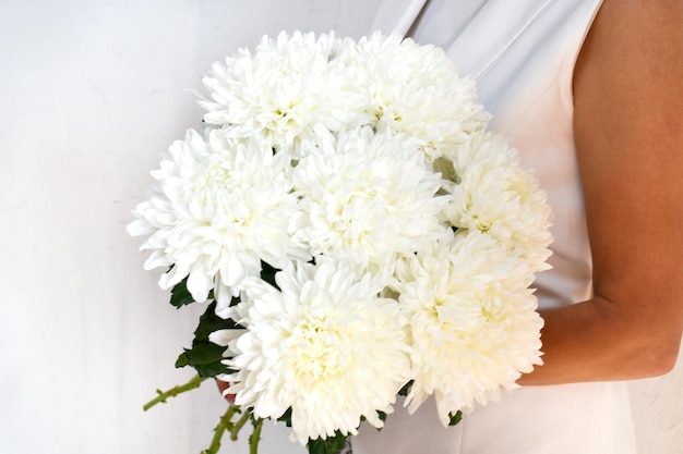 Donna con bouquet di crisantemi bianchi Bellissimi fiori bianchi freschi per le vacanze Donna con bellissimi fiori bianchi al chiuso