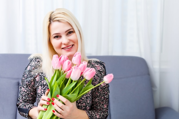 Donna con bouquet di fiori di primavera. Felice modello sorpreso donna annusare i fiori. Festa della mamma. Primavera