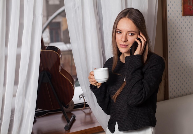 Donna con caffè in piedi dietro la chitarra e bere