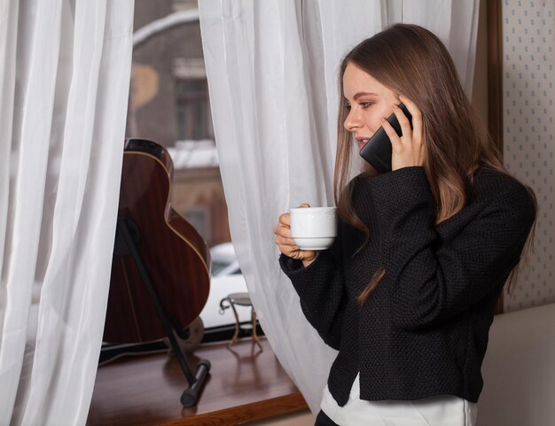 Donna con caffè in piedi dietro la chitarra e bere