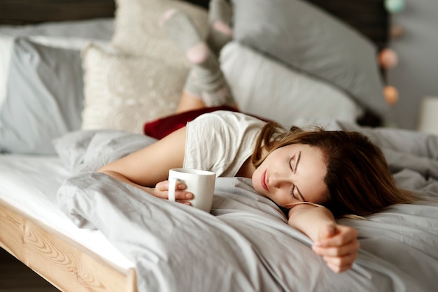 Donna con caffè sdraiata a letto