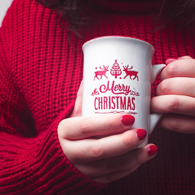 Donna con caldo boccale Buon Natale e maglione rosso