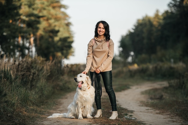 Donna con cane golden retriever che cammina sul sentiero nel bosco