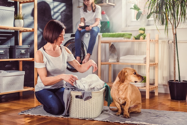 Donna con cane ordinamento vestiti sul pavimento