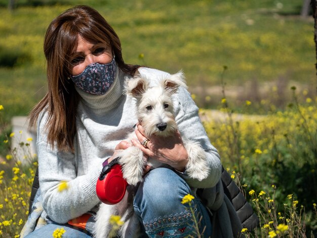 Donna con cane Schnauzer bianco nel campo di fiori gialli yellow