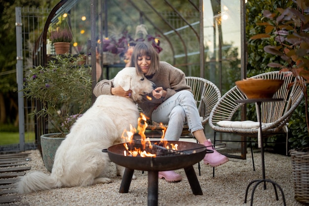 Donna con cane vicino al fuoco in giardino