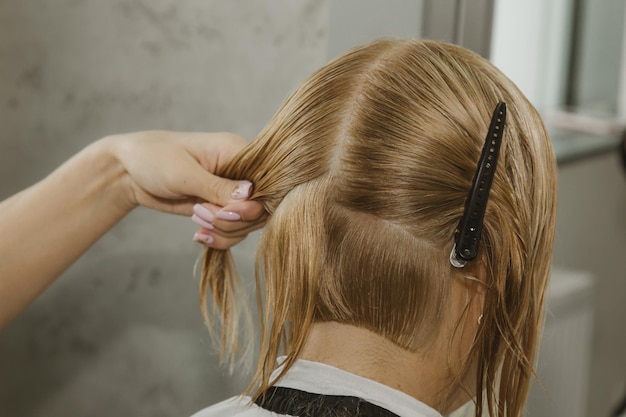 Donna con capelli biondi di media lunghezza Con un taglio di capelli corto dal parrucchiere dallo stilista usando le forbici Procedure di cura Il maestro si accorcia i capelli