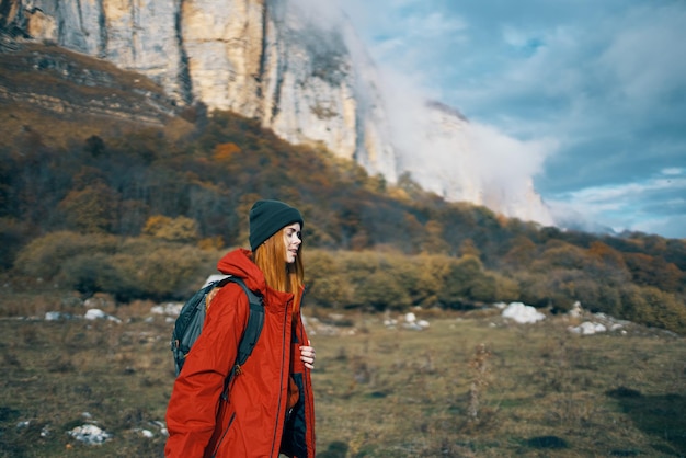 Donna con cappelli a giacca con uno zaino sulla schiena cammina in autunno in montagna e in natura foto di alta qualità