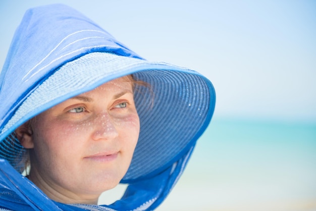 Donna con cappello blu su sfondo blu cielo e acqua Concetto di vacanza